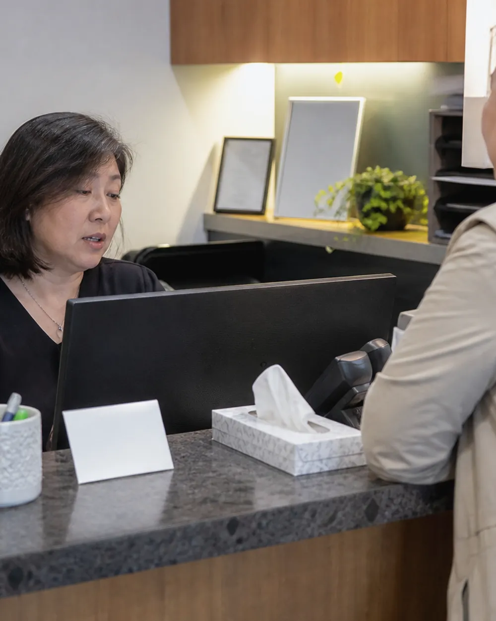 A patient asking a question at a clinic reception desk